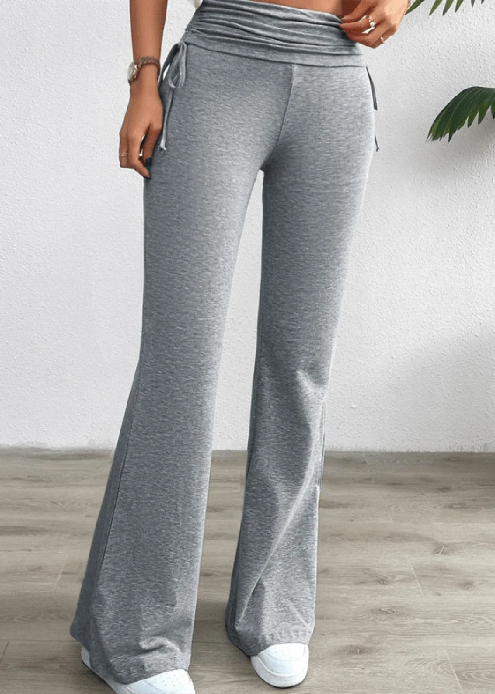 Gray flared yoga pants with drawstring waist detail and white sneakers