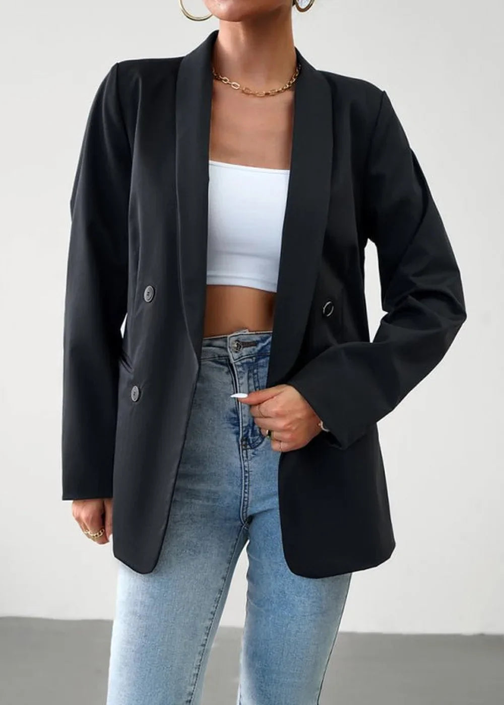 Black double-breasted blazer with a satin lapel and button details, worn over a white crop top and light wash jeans.