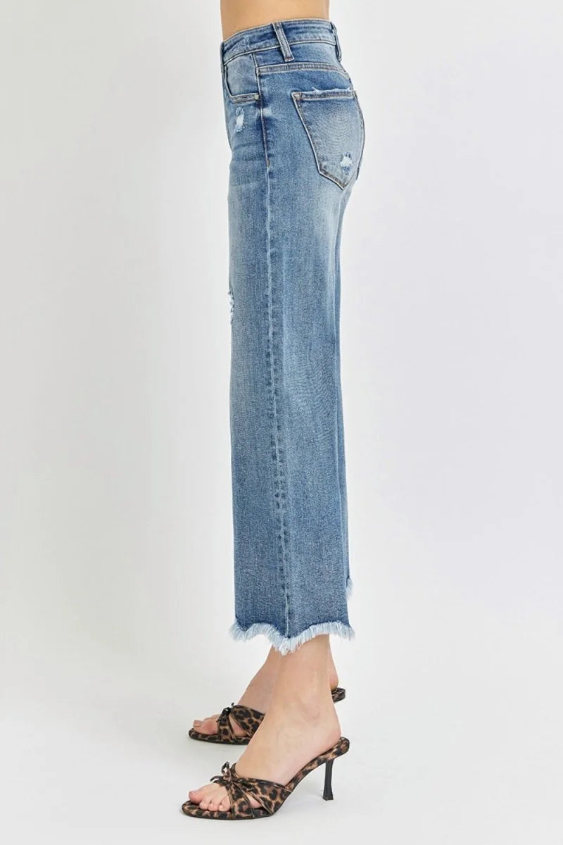 Distressed denim jeans with frayed hem and leopard print heels.