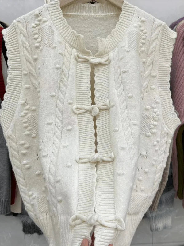 Cream cable knit vest with bobble texture and frog closures.