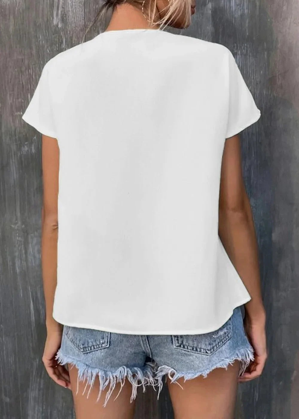 Back view of a white t-shirt with a frayed hem denim shorts on a woman.