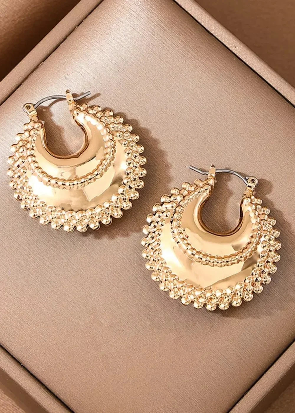 Gold-tone crescent hoop earrings with beaded trim and textured center.