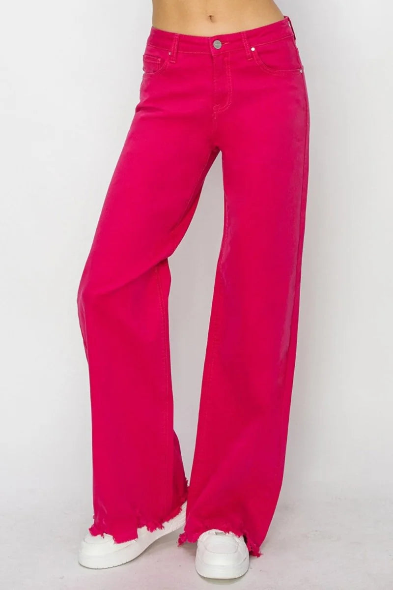 Bright pink wide-leg jeans with frayed hem, on model wearing white sneakers.