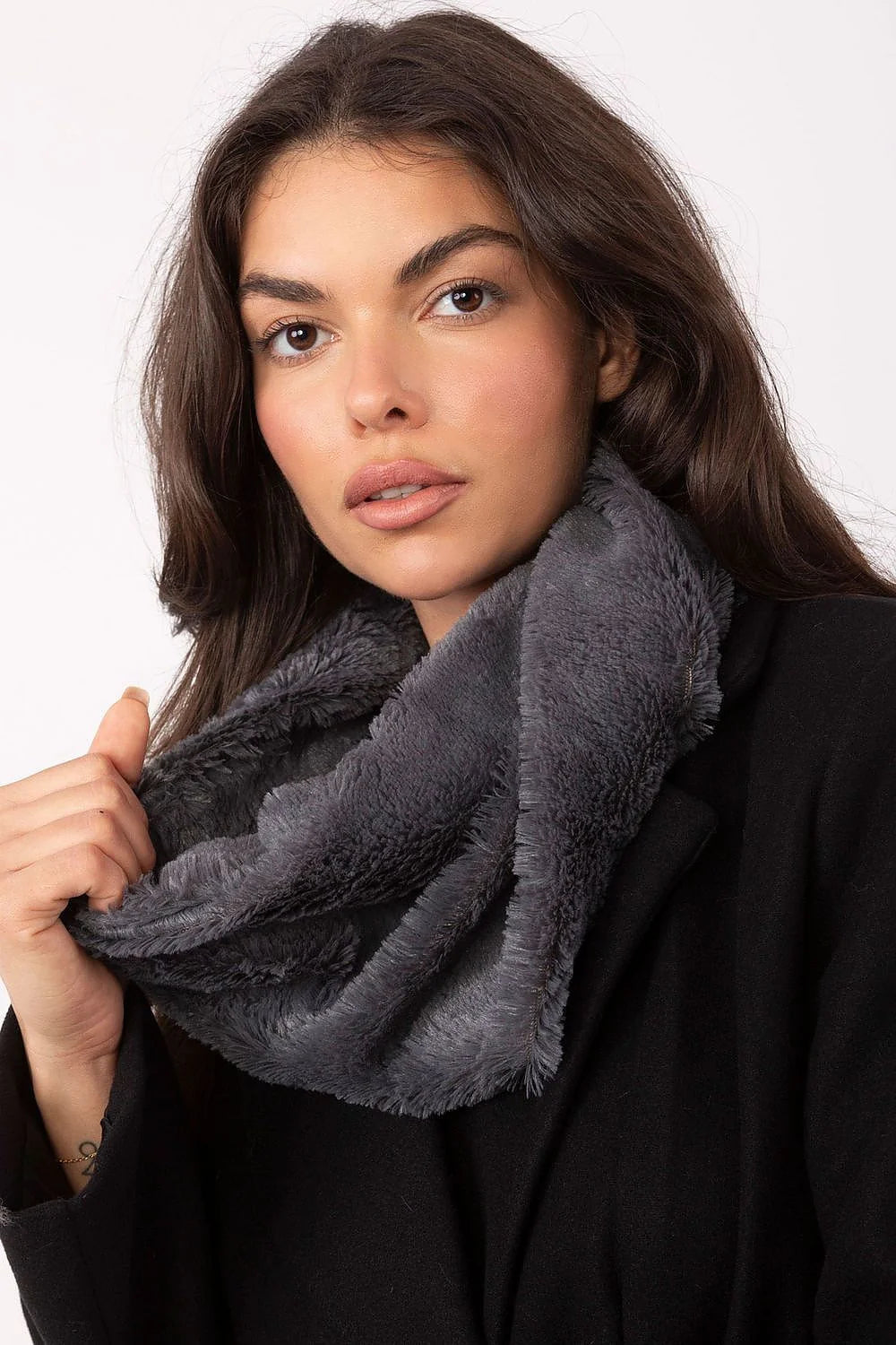 Close-up of a woman wearing a black coat and a soft, plush gray infinity scarf with frayed edges.
