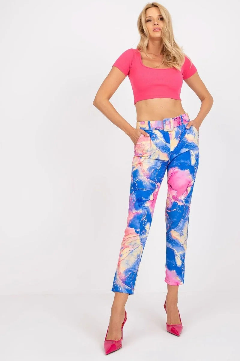 Bright blue, pink, and yellow marbled print pants with a matching belt, on a model.