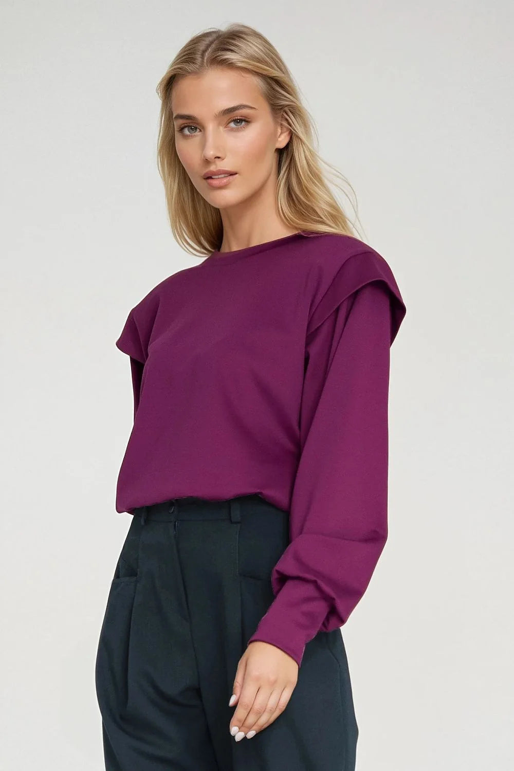 Deep magenta long-sleeve top with layered shoulder detail, worn with dark green wide-leg trousers.