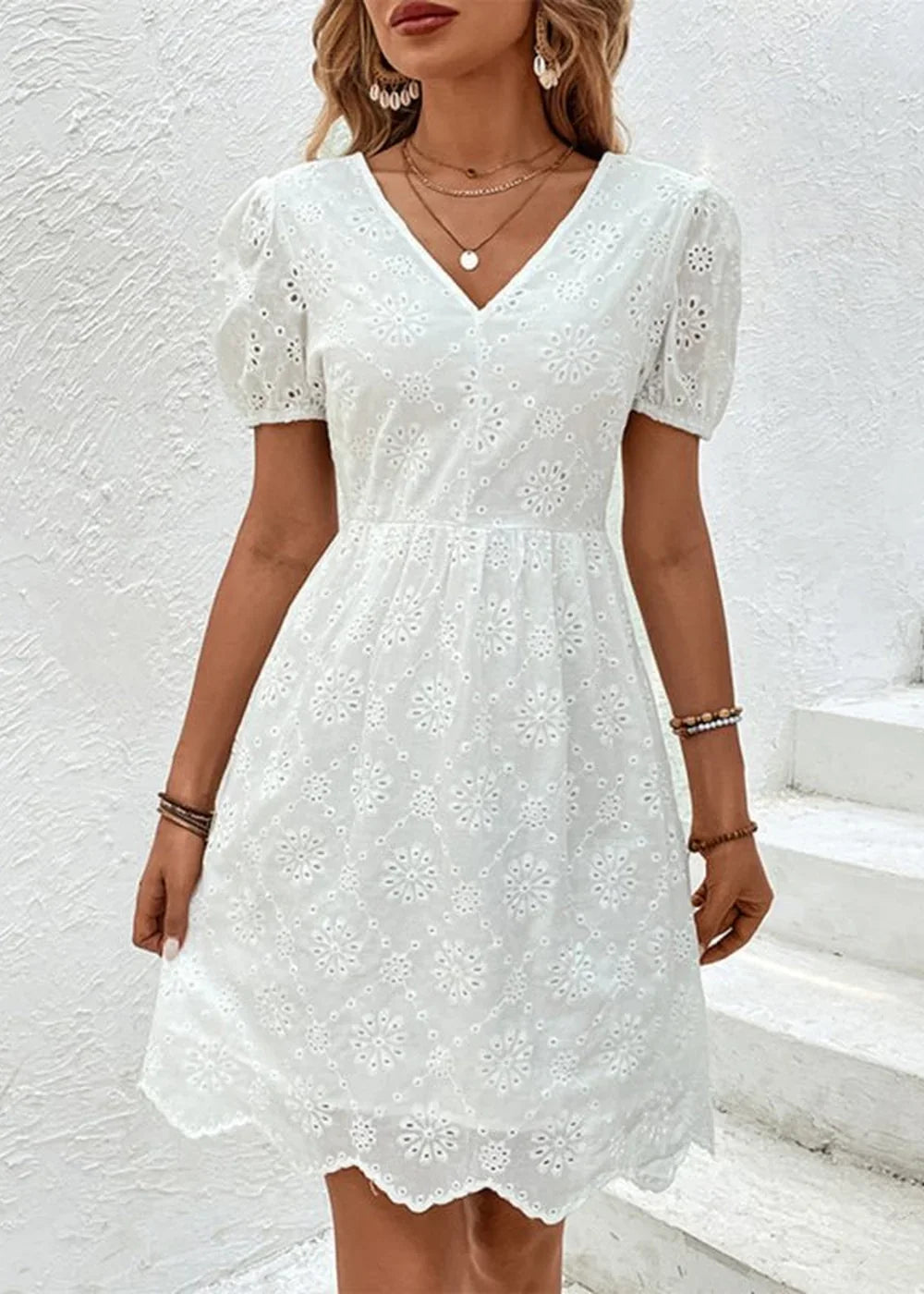White eyelet dress with puff sleeves and a floral pattern, on a model.