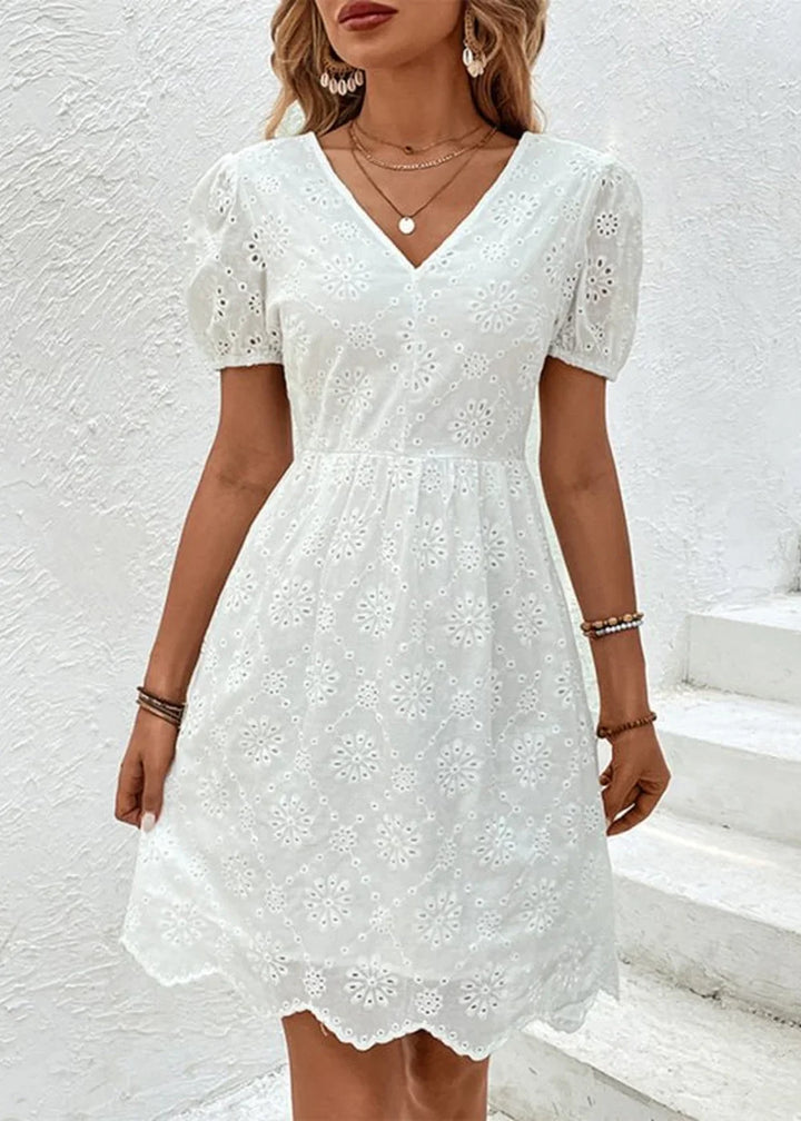 White eyelet dress with puff sleeves and a floral pattern, on a model.