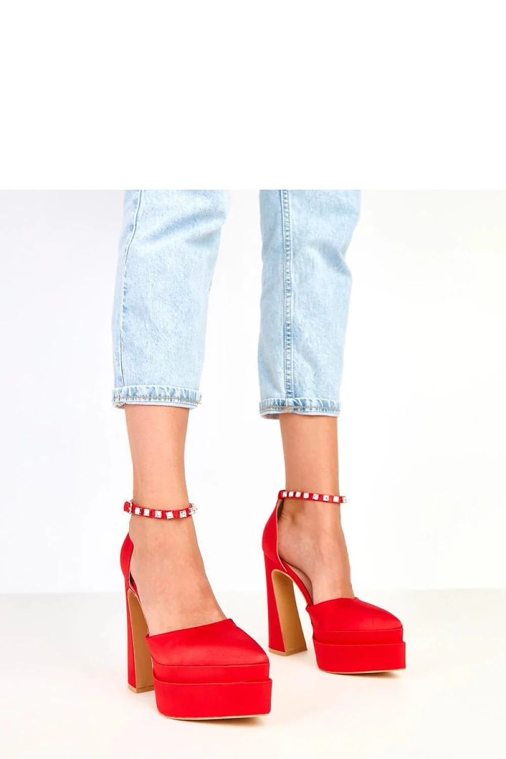 Red satin platform heels with ankle strap and jeweled details on a model.