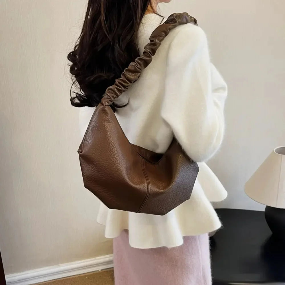 Brown pebbled PU leather shoulder bag with ruched strap, worn with a white sweater.