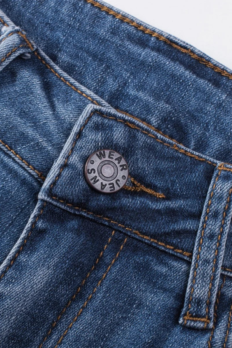 Close-up of a button on dark wash denim jeans with visible stitching and "WEAR JEANS" text.