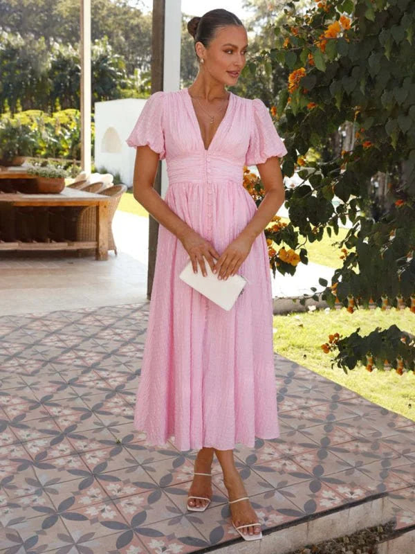 Pink textured midi dress with V-neck, puff sleeves, button front, and white sandals.