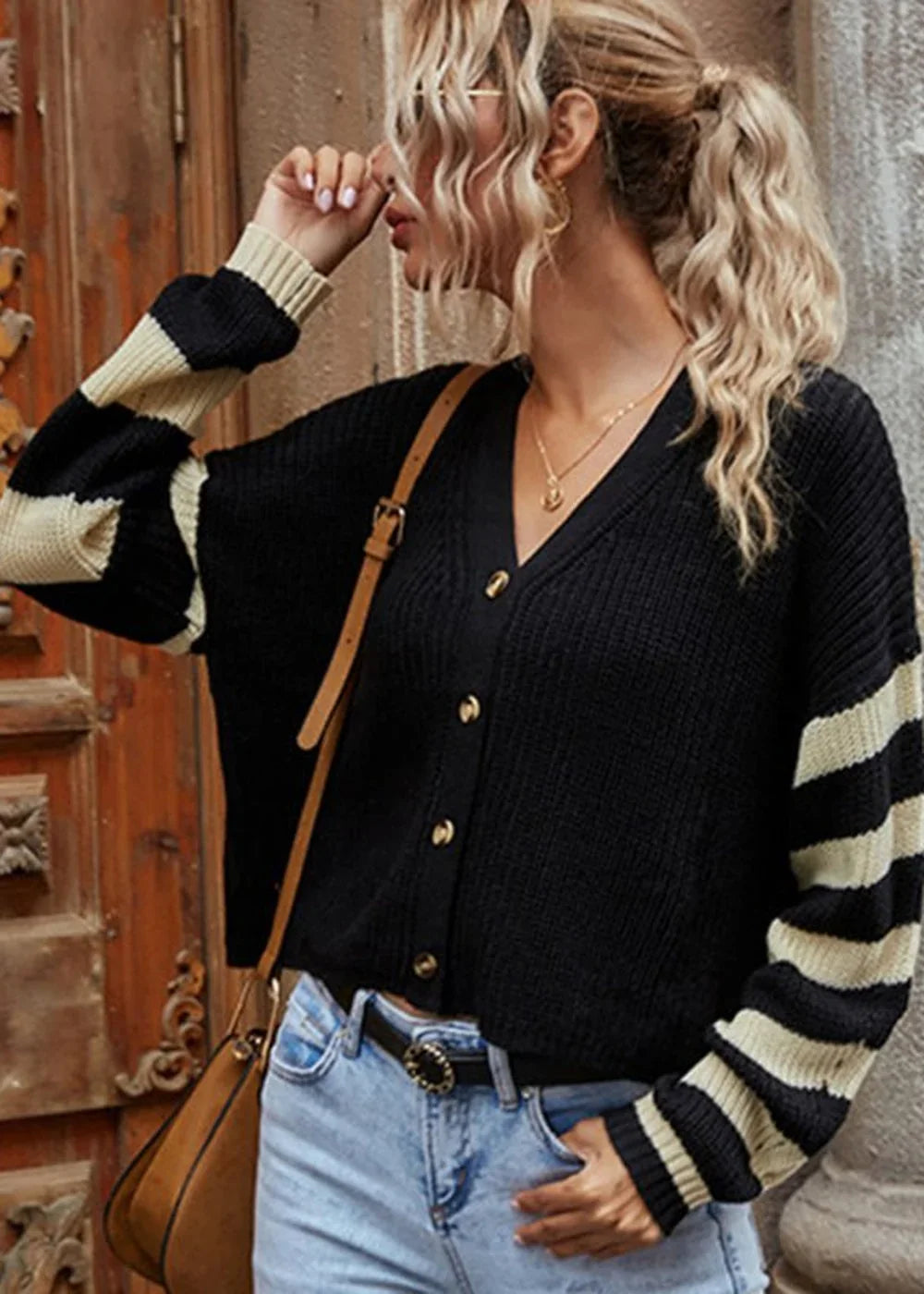 Black cardigan with cream and black striped sleeves, v-neck, and gold buttons.