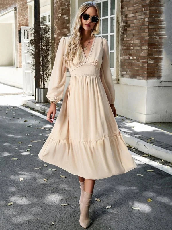 Cream v-neck midi dress with ruffled hem and balloon sleeves on a model.