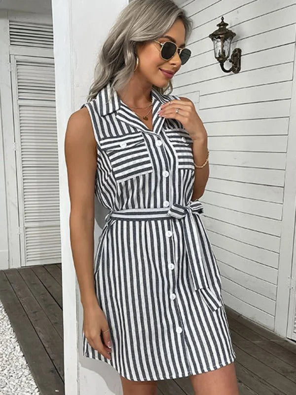 Woman in a black and white striped shirt dress with a tie waist and gold accessories.