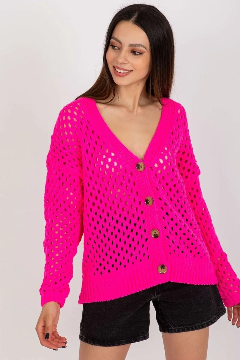 Bright pink crochet knit cardigan with brown button closure and black denim shorts on a model.
