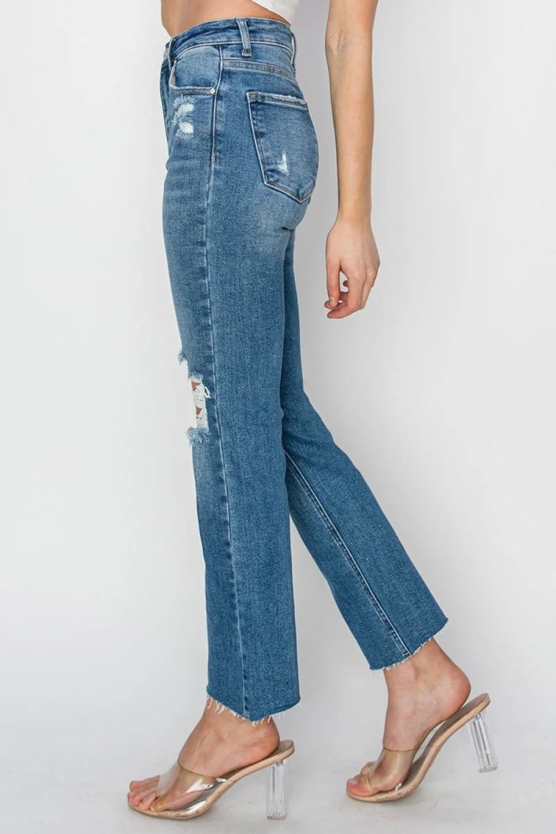 Medium wash distressed denim jeans with frayed hem, shown on model.