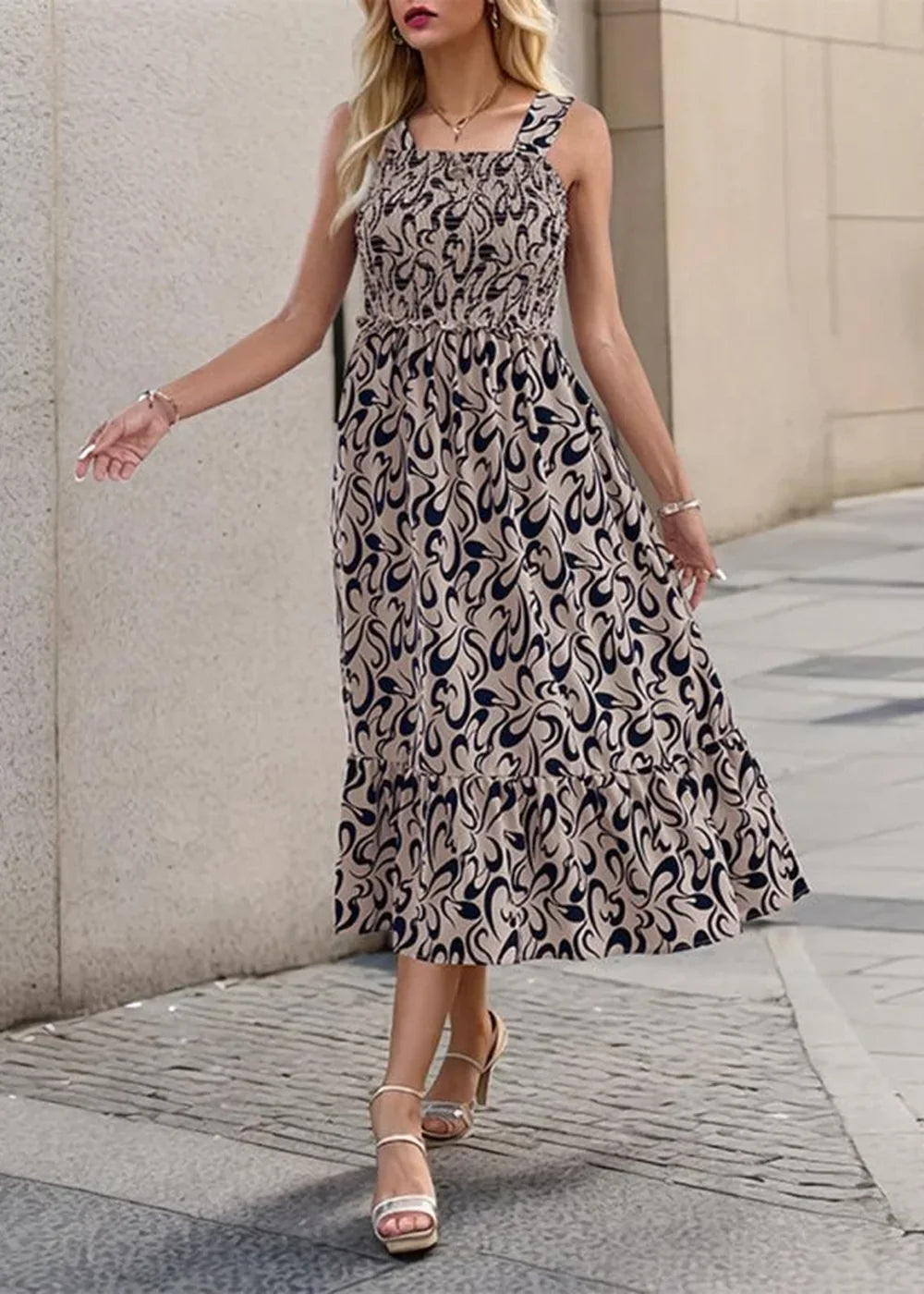 Beige and navy abstract print smocked midi dress with tiered hem and strappy heels.