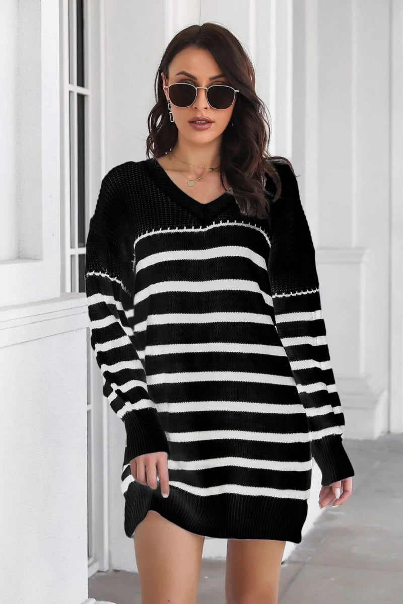 Black and white striped sweater dress with V-neck and long sleeves on a model.