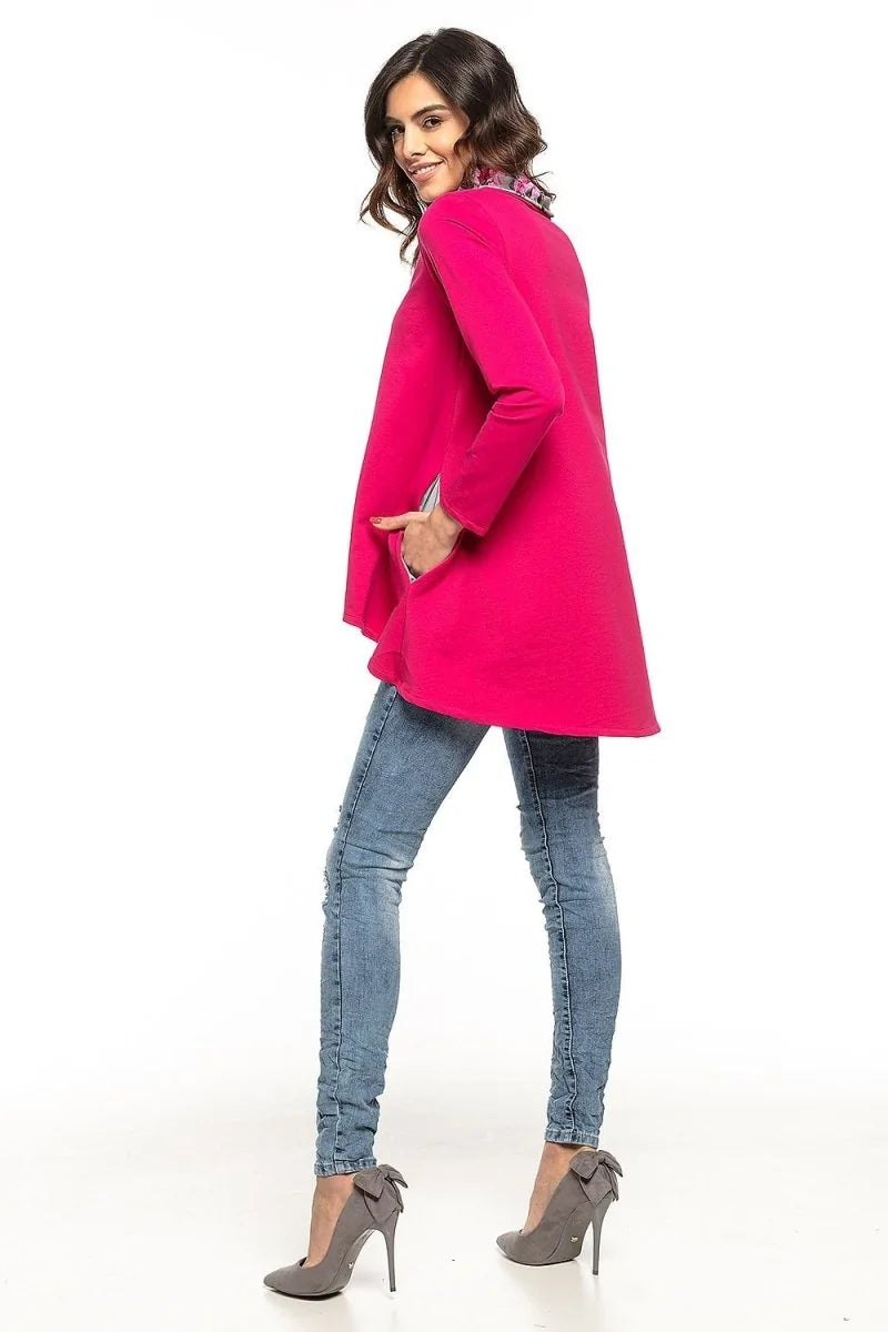 Woman in a bright pink tunic with pockets, blue distressed jeans, and grey bow heels.