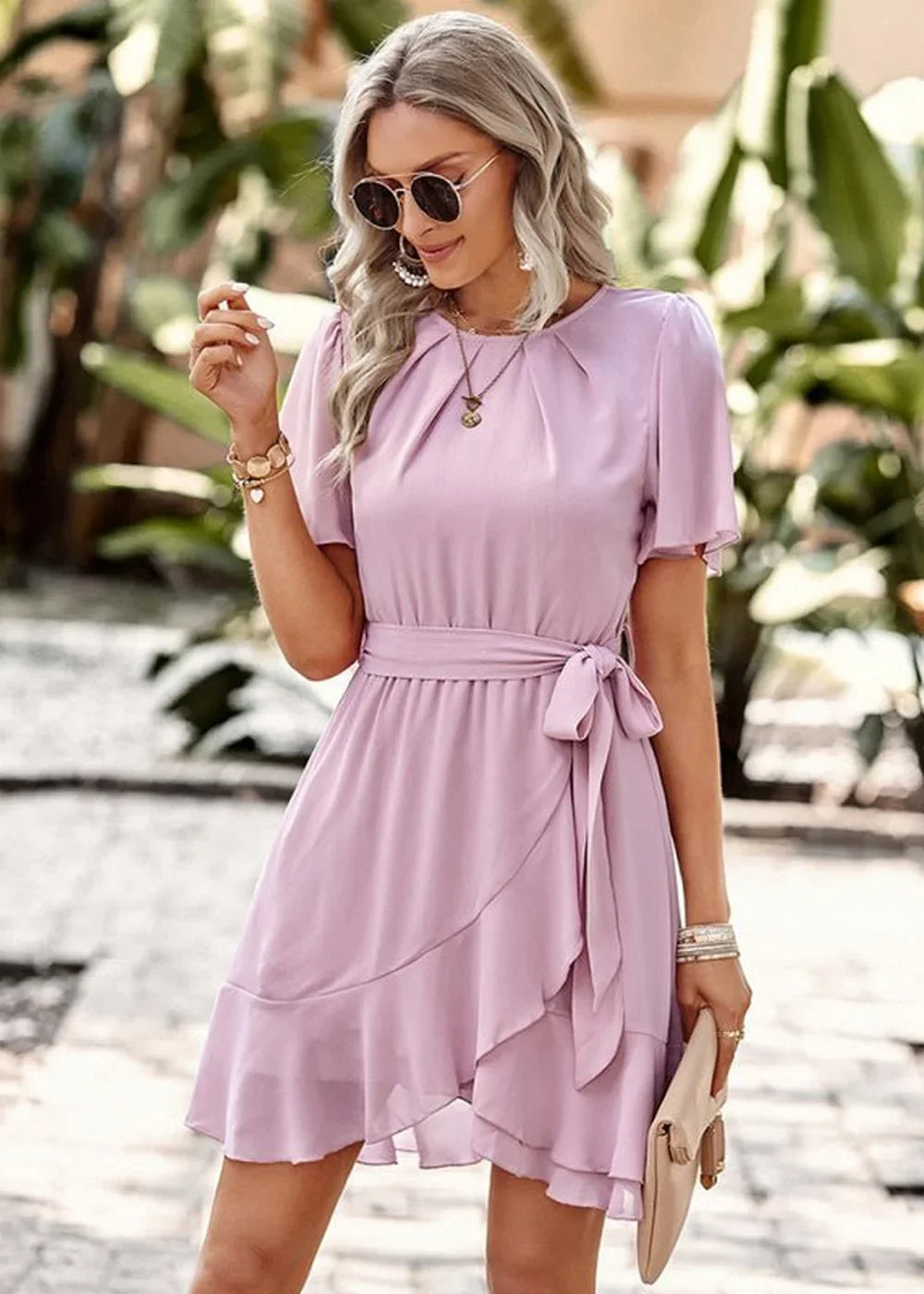 A light purple wrap dress with flutter sleeves, a tie waist, and ruffled hem, on a woman.