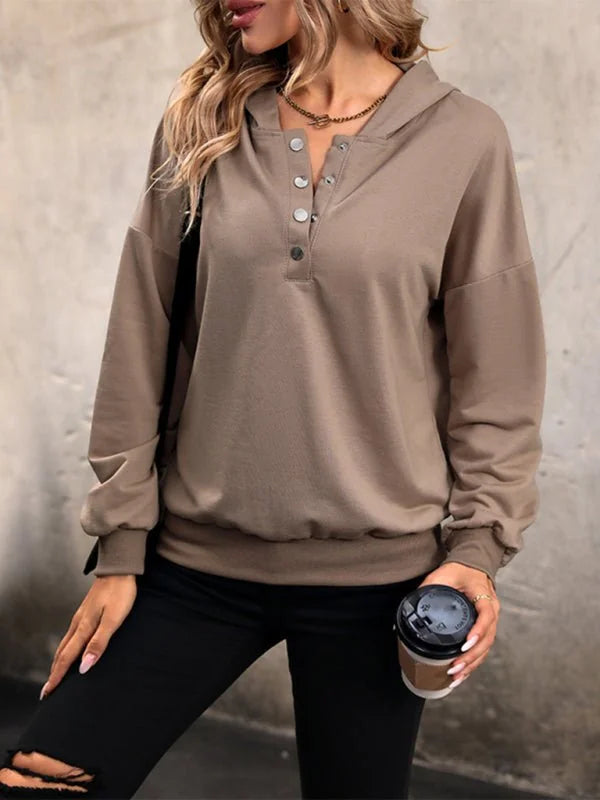 Taupe hooded sweatshirt with button-up neckline, on model wearing black ripped jeans.