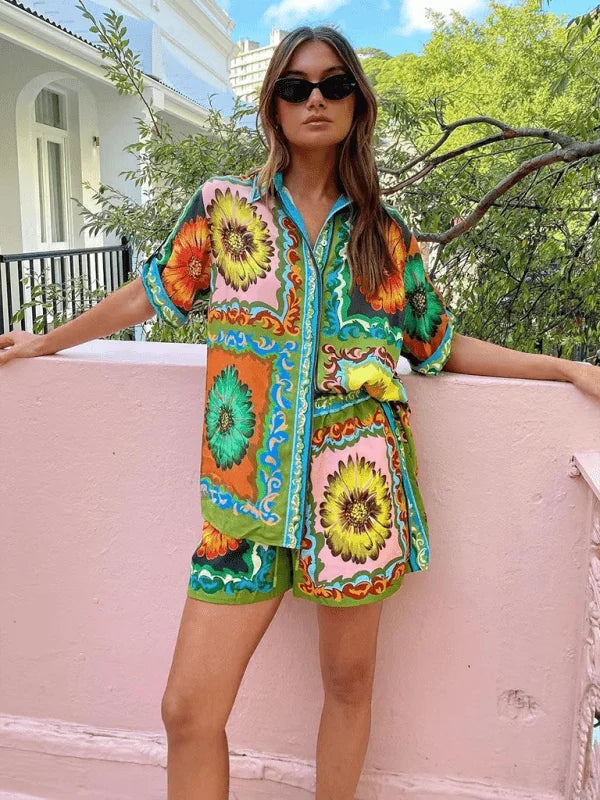 Model in a vibrant floral print linen short suit with a collared, button-up top and matching shorts.