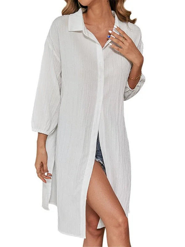 White textured longline button-up shirt dress with side slits, worn over denim shorts.