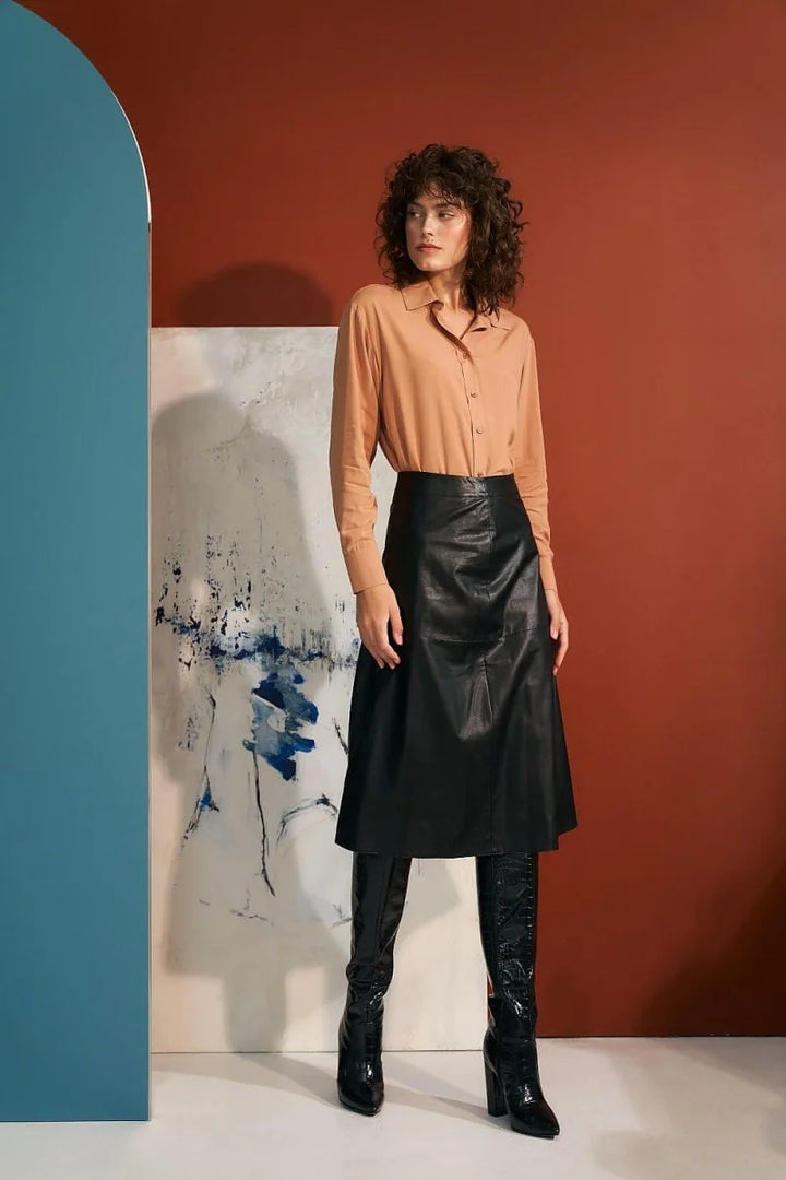 Black faux leather midi skirt with a-line silhouette and knee-high croc-embossed boots.