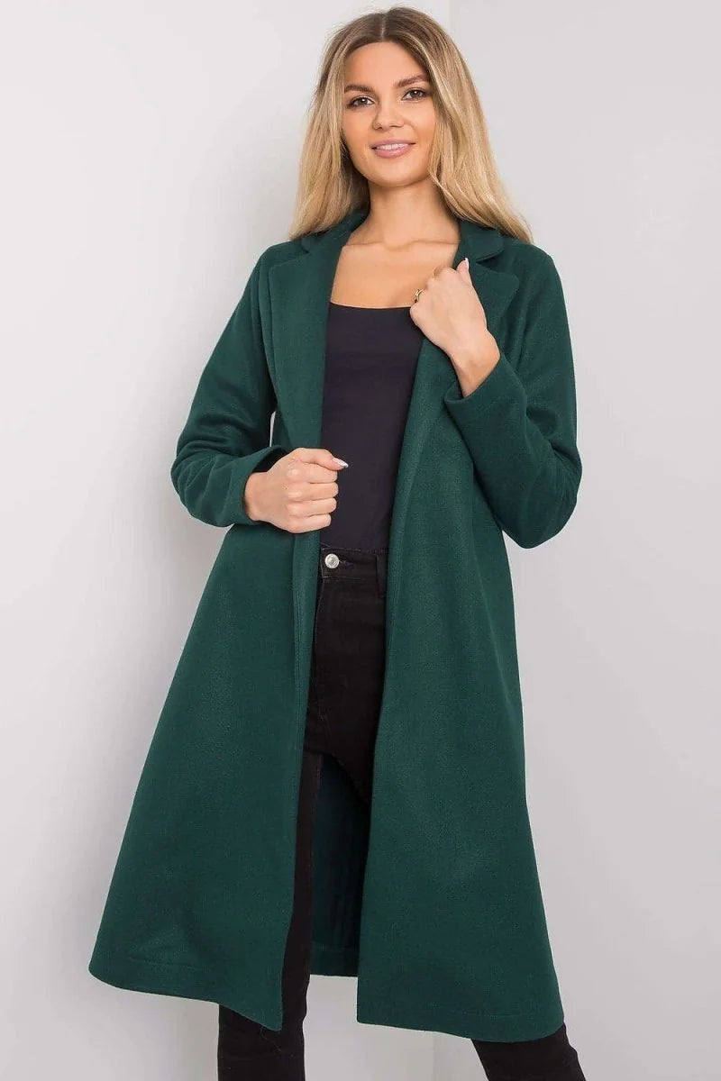 Woman in a dark green long coat and black pants, showcasing the coat's flowing silhouette.