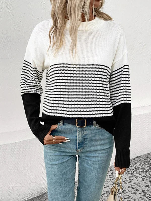 White and black striped knit sweater with long sleeves, worn by a model with light wash jeans.