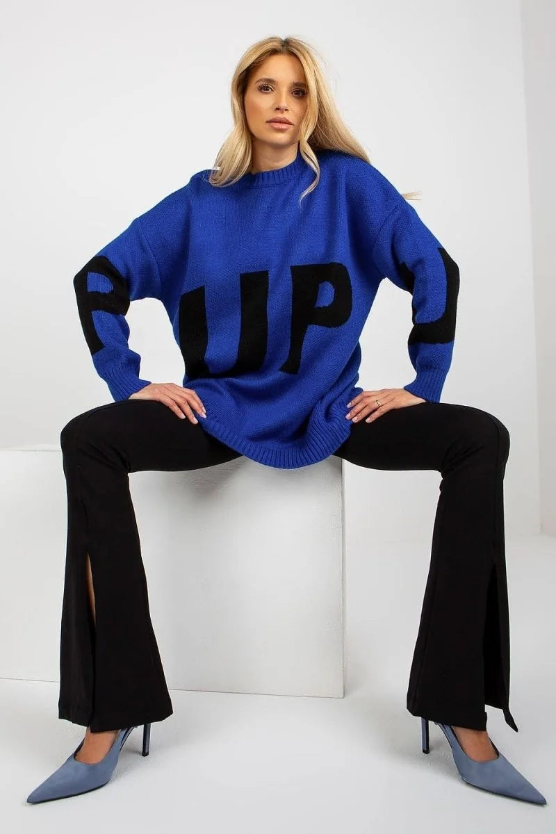 Royal blue chunky knit sweater with black "RUP" graphic, paired with black flared pants with side slits.