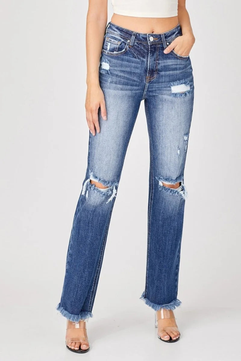 Distressed straight-fit blue denim jeans with frayed hems and clear strap heels.