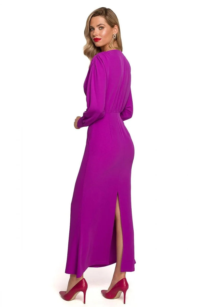 A vibrant magenta maxi dress with long sleeves, a cinched waist, and a thigh-high slit, worn by a model.
