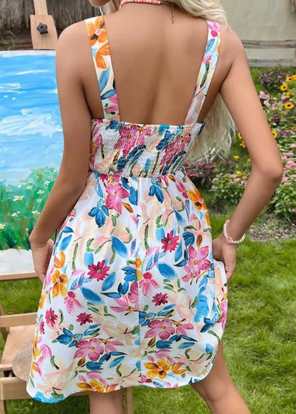 Back view of a white floral print dress with smocked bodice and spaghetti straps.
