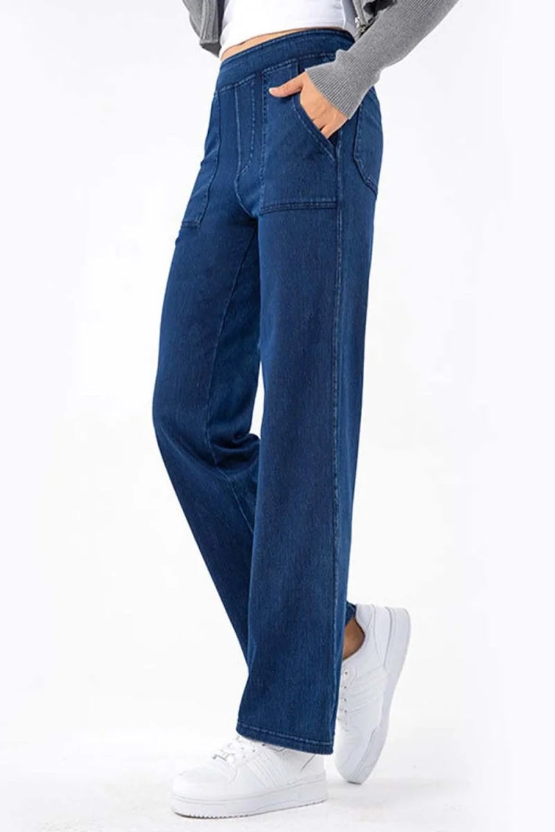 Blue denim wide-leg pants with front pockets and a relaxed fit, worn with white sneakers.