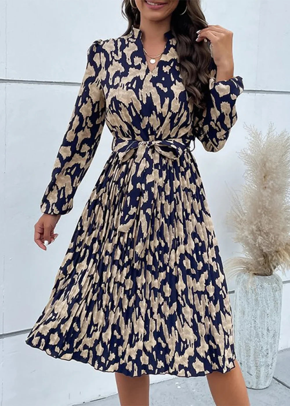 Navy blue dress with beige abstract print, long sleeves, pleated skirt, and tie waist.