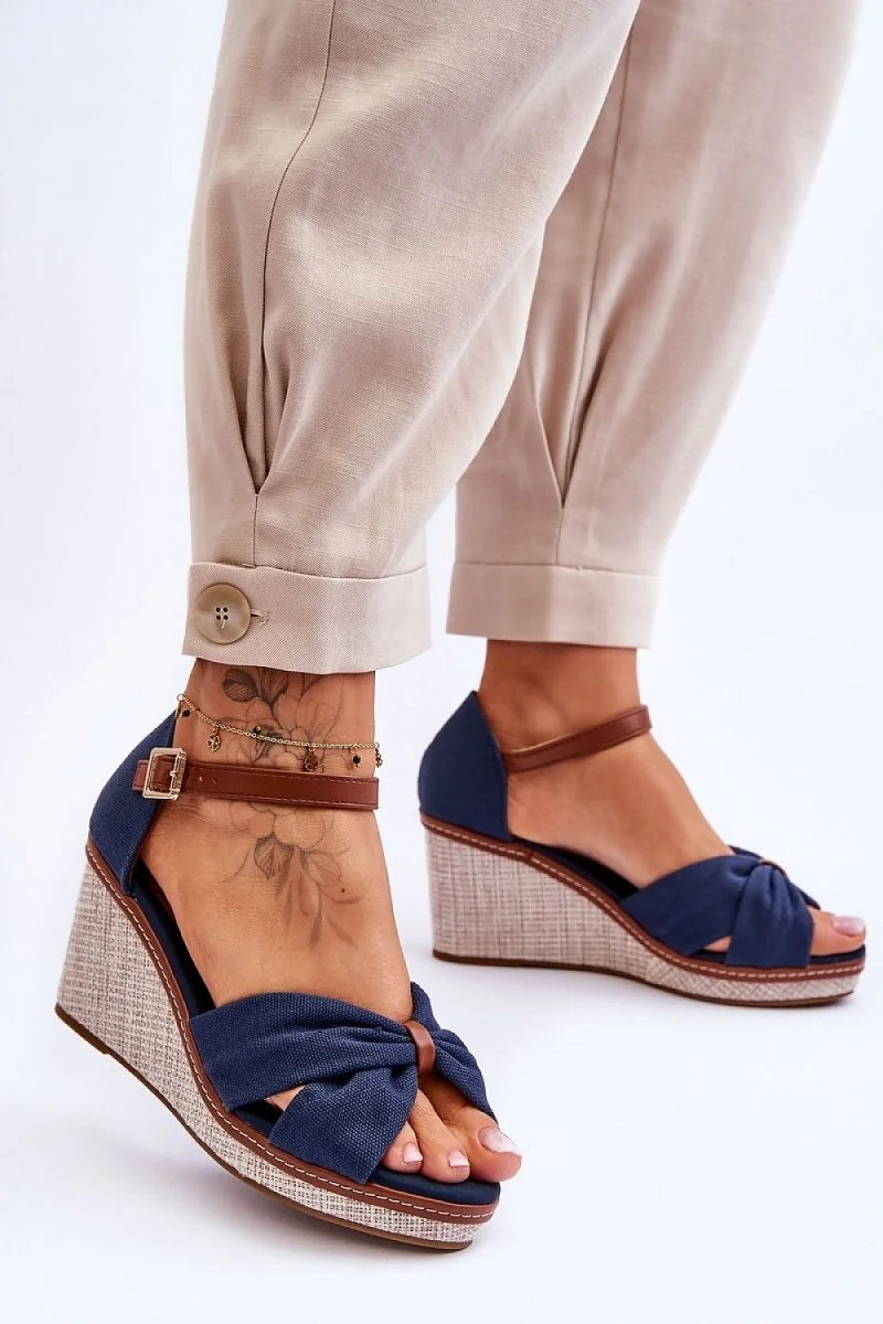 Navy blue fabric wedge sandals with brown ankle straps and a textured wedge.