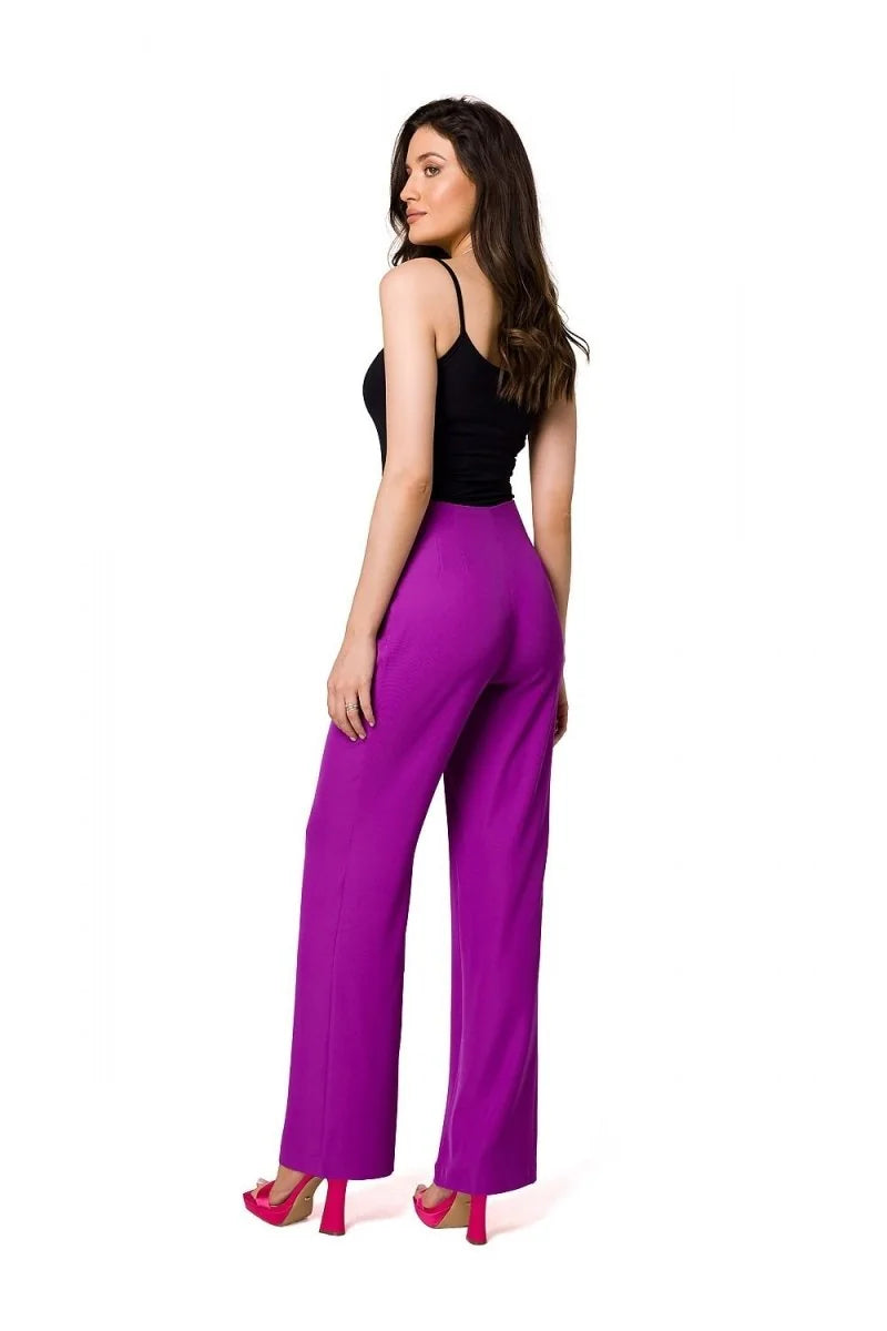 Woman in black camisole and vibrant purple wide-leg pants with high heels, shown from the side.