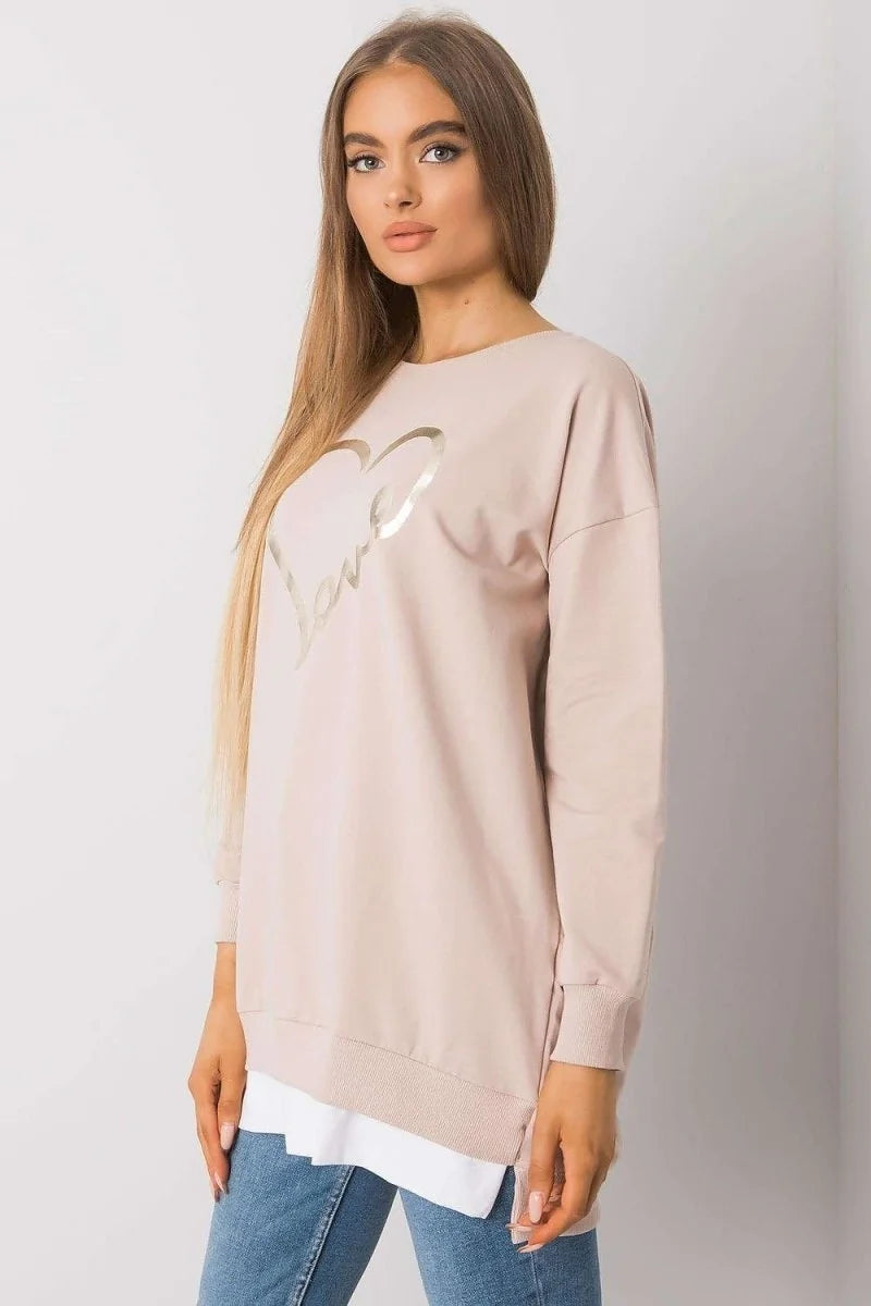 Loose-fitting beige sweatshirt with a gold heart and "love" graphic on a model.