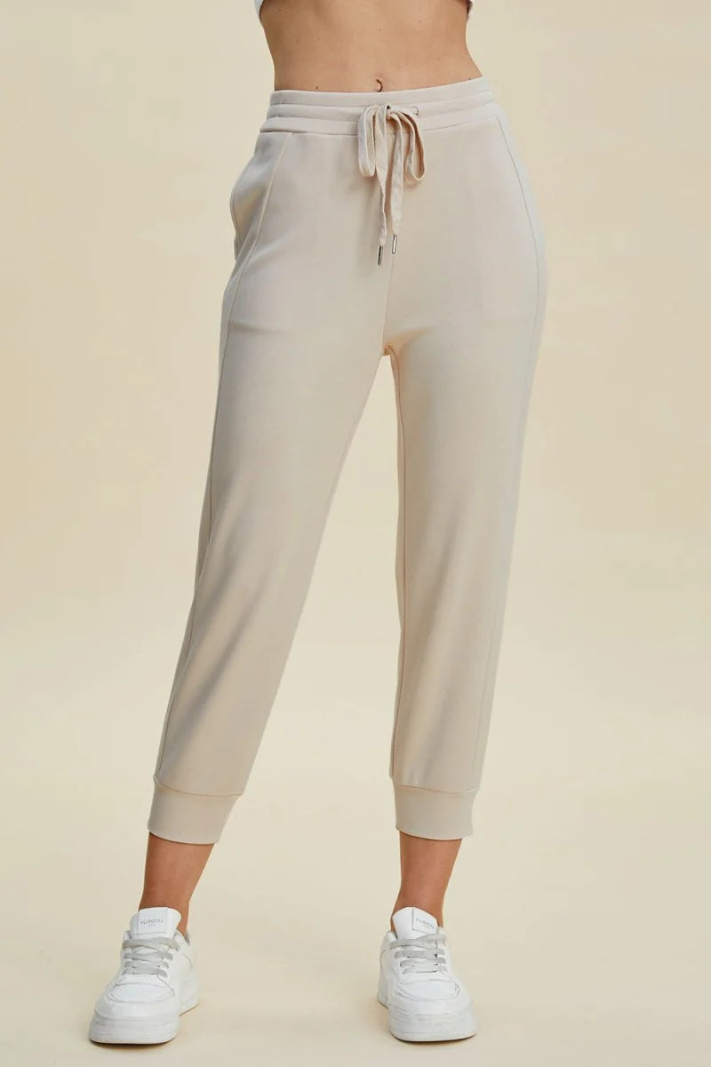 Beige knit joggers with drawstring waist and cuffed ankles, on model.