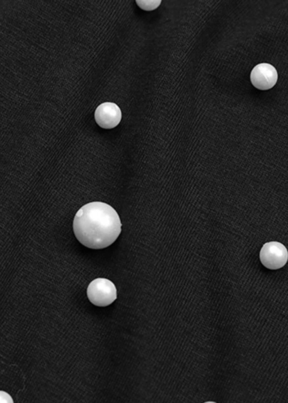 Black mesh fabric with scattered pearl embellishments, close-up detail.