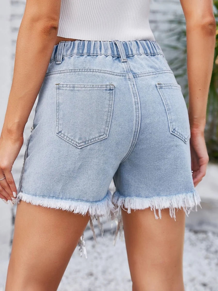 Light wash denim shorts with a frayed hem and elastic waistband, shown from the back.
