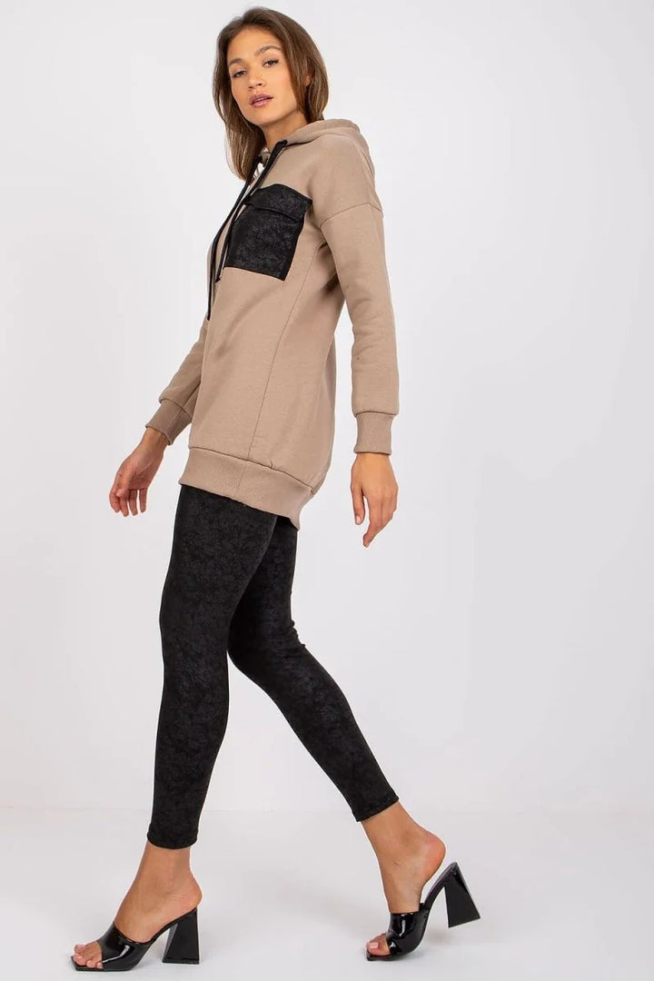 Black patterned leggings with a textured finish on a model wearing a beige hoodie and black heels.