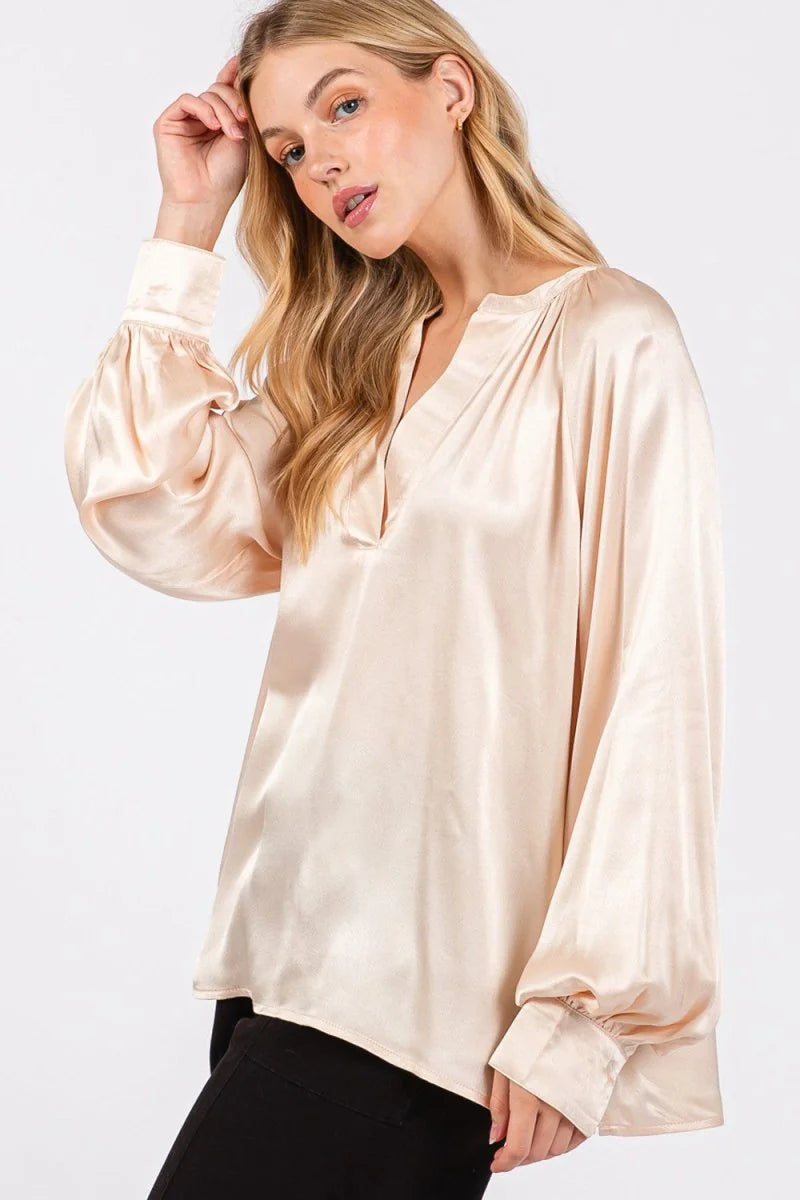 Sheer champagne satin blouse with relaxed fit, V-neck, and voluminous bishop sleeves.