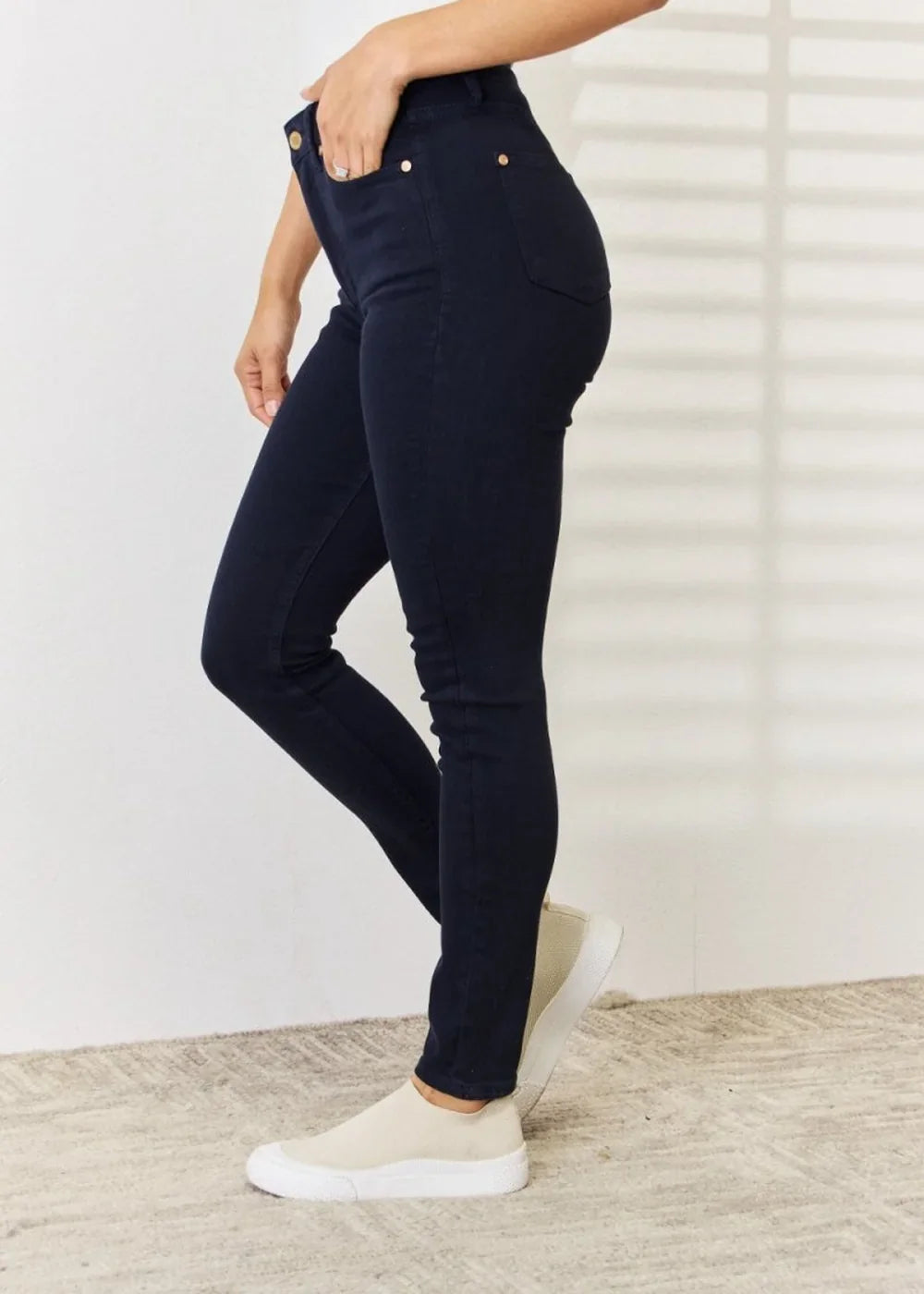 Navy blue cotton blend skinny jeans with gold button details on a model.