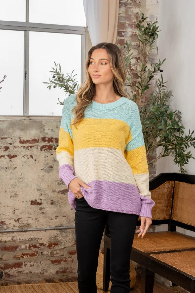 Striped knit sweater in lilac, cream, yellow, and mint green with a relaxed fit on a model.
