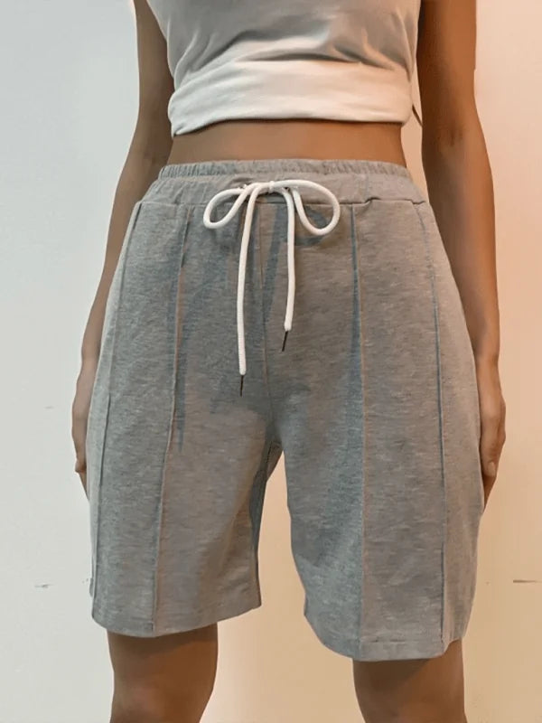 Light grey sweat shorts with vertical seams and a drawstring waist, shown on a model.