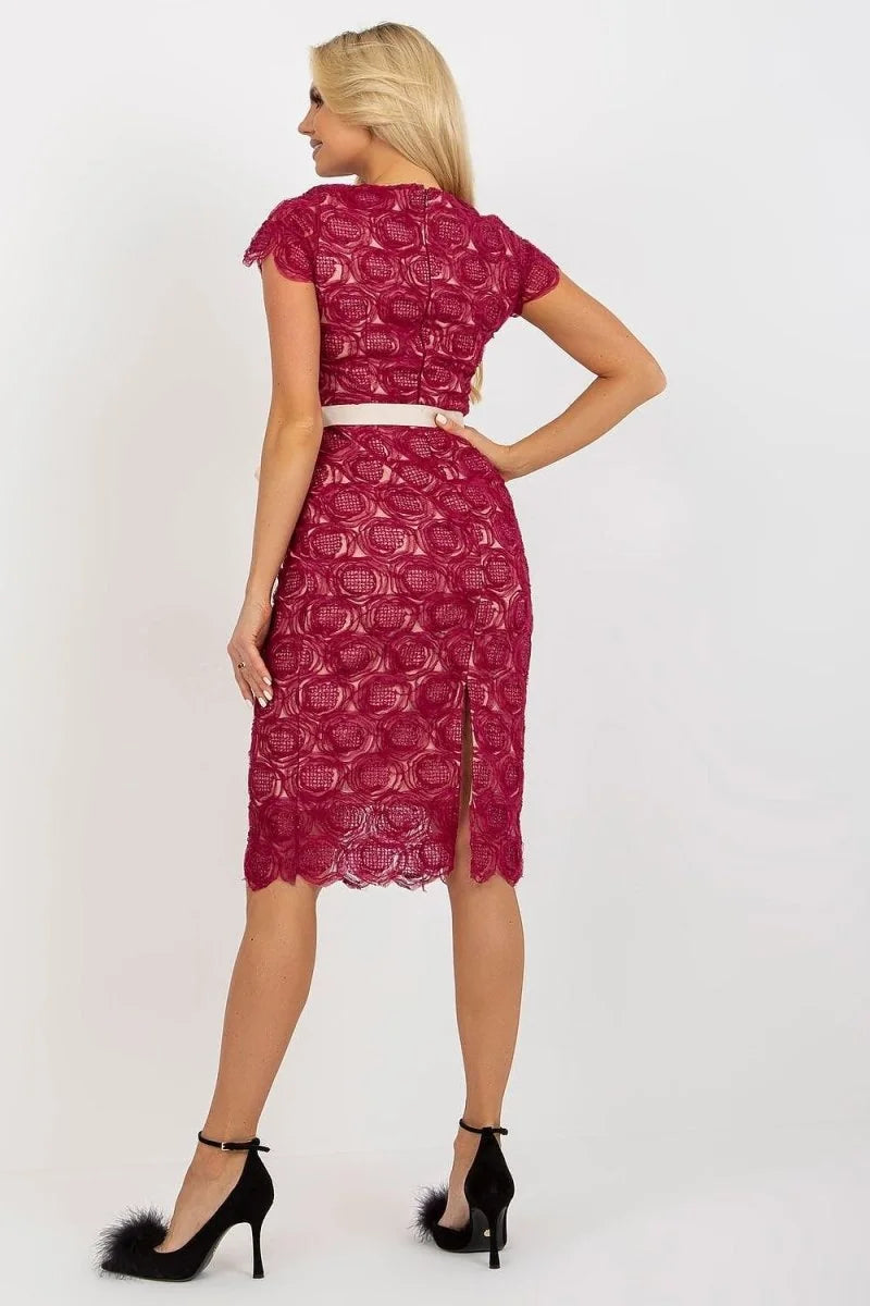 Back view of a woman in a short-sleeved, knee-length cranberry lace dress with a white belt and black heels with fluffy ac...