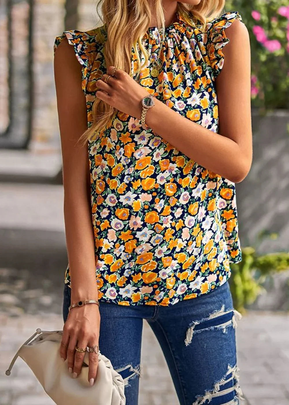 Navy blue sleeveless top with a vibrant floral print in yellow, orange, and white, featuring ruffled shoulders.